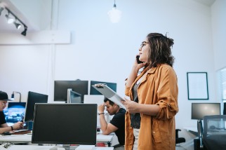 Safety professional woman holding a clipboard and talking on the phone in an office
